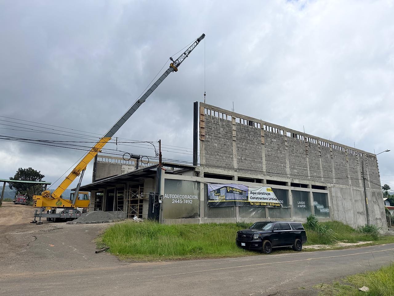Grúa de brazo largo alcanzando la cubierta de un edificio de dos niveles en construcción