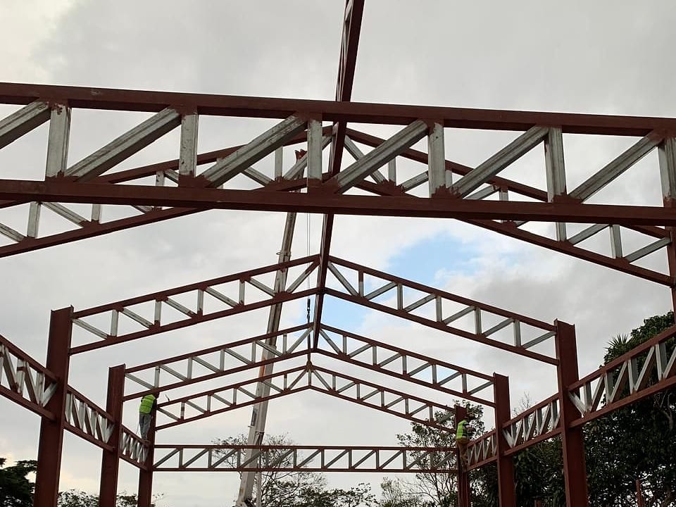 Cerchas metálicas rojas colocadas sobre columnas durante el montaje de una nave