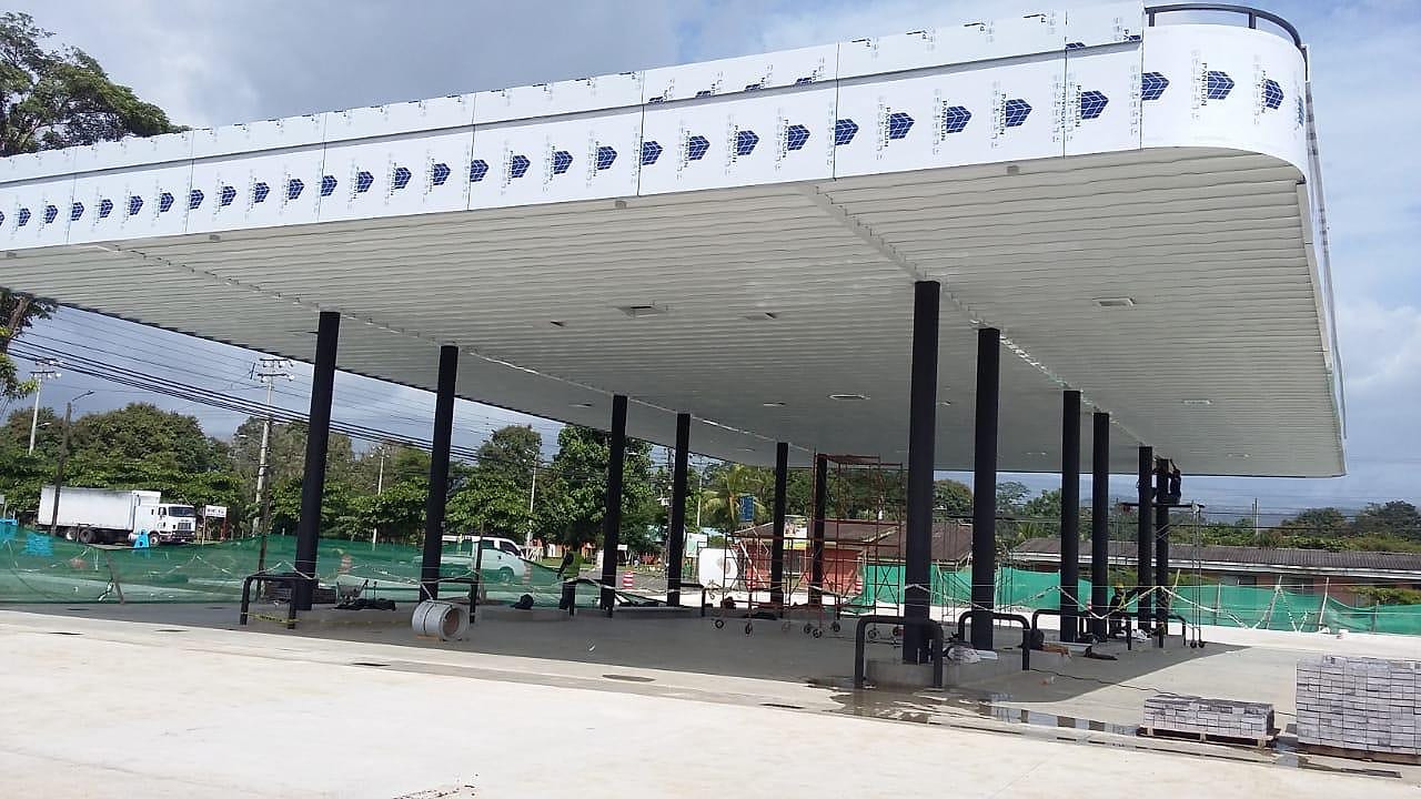 Marquesina blanca de borde curvo sobre columnas metálicas en una estación de servicio