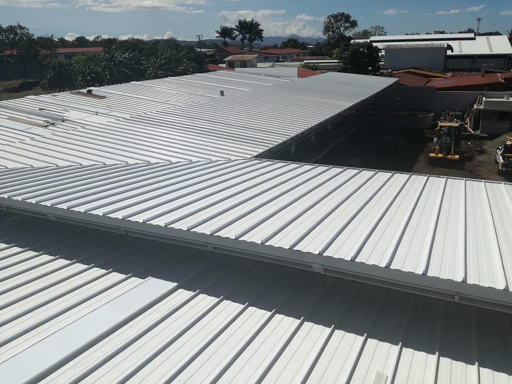 Cubierta metálica nueva recién instalada sobre un edificio, con las montañas al fondo