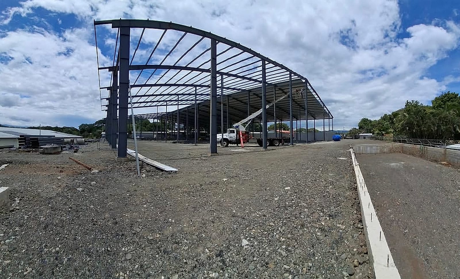 Bodega metálica en montaje, con cerchas a dos aguas y clavadores contra el cielo