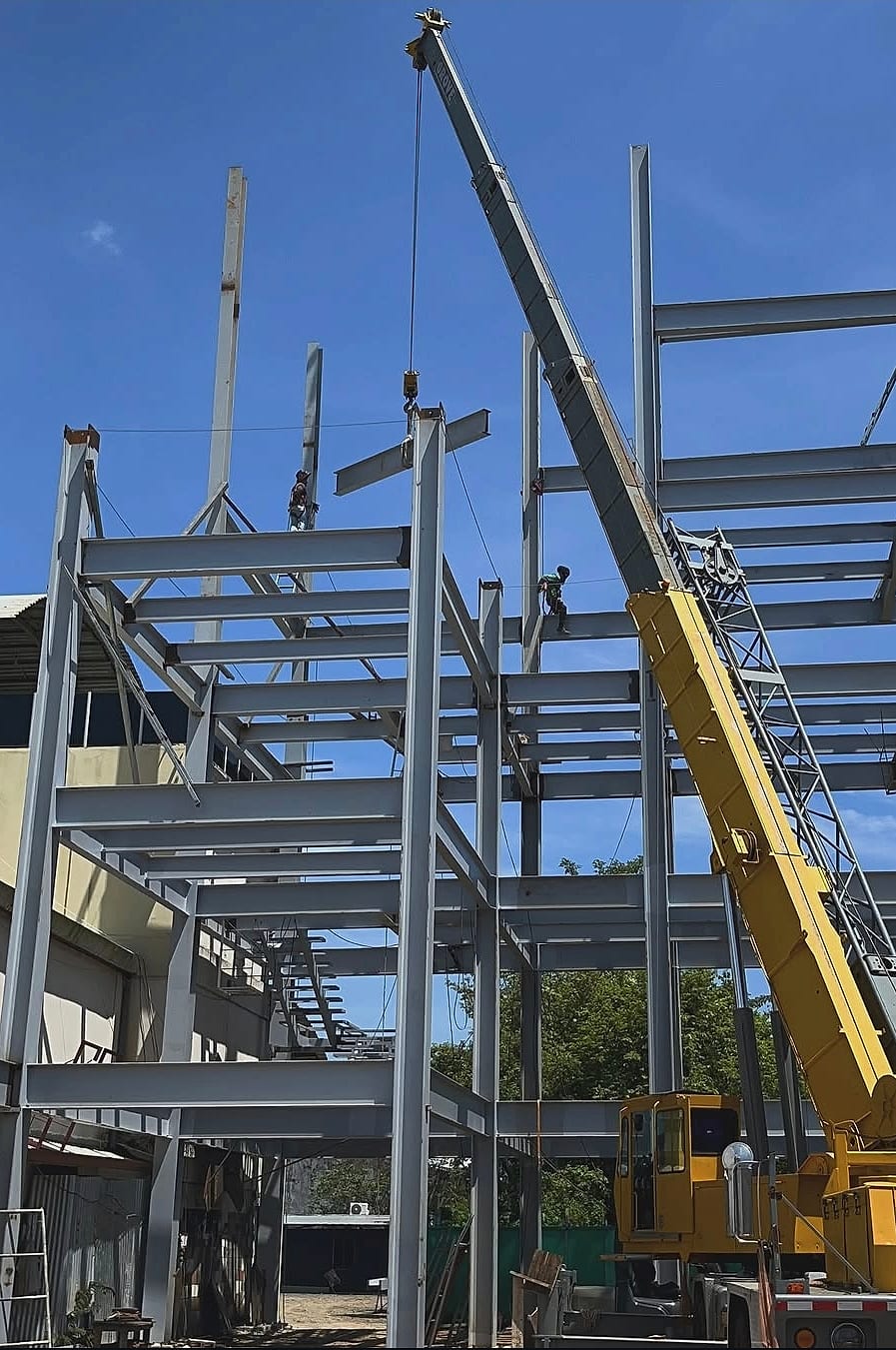 Grúa izando una viga de acero sobre una estructura de varios niveles